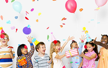 Group of kids celebrate birthday party together with presents, confetti and balloons
