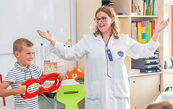 Boy next to his mad scientist teacher holding 2 red horseshoe magnets together