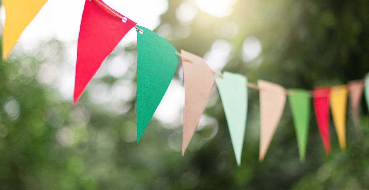 Colorful flags at sunset in garden. Concept of celebration or party. Paper festive decoration outdoor.