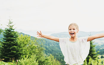 Little kid girl hiking in mountains, arms up wide open