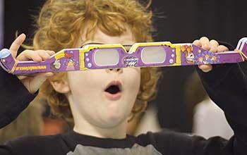 Boy looking surprised holding a stack of Mad Science diffraction glasses