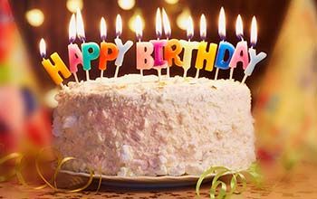 A birthday cake with lit candles that say happy birthday