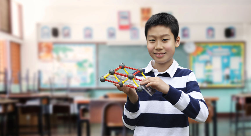 Boy in stripe short holding a toy bridge.